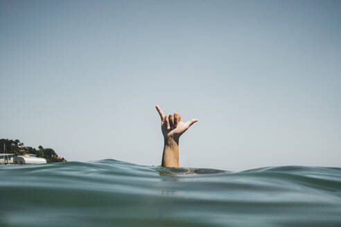 Womans hand making surfer's sign in water - MTBF00507