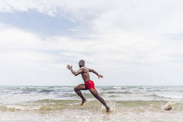 Sportlicher Mann läuft am Strand - OCMF01397