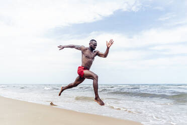 Sportlicher Mann läuft am Strand - OCMF01399