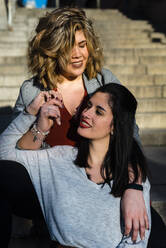 Nahaufnahme eines lesbischen Paares, das auf einer Treppe in der Stadt sitzt - JMPF00072
