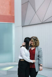 Romantisches Paar umarmt, während gegen moderne Gebäude in der Stadt stehen - JMPF00078