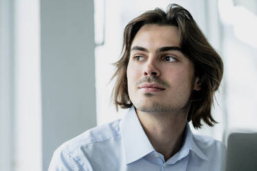 Close-up of thoughtful businessman looking away while sitting in cafe - KNSF08118