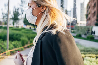 Close-up of businesswoman wearing mask walking in city - MEUF01091
