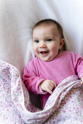 Portrait of happy baby girl in pink pyjama lying on bed - GEMF03889