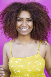 Close-up of cheerful woman with afro hair wearing yellow dress while standing outdoors - JSMF01588