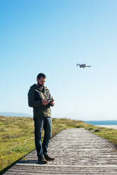 Junger Mann fliegt eine Drohne in der Nähe des Strandes - CAVF86568