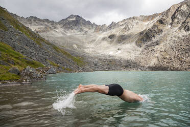 Man dives in for swim in Upper Reed Lake, Talkeetna Mountains, Alaska - CAVF86649