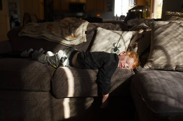Kleinkind Junge schläft auf dem Bauch auf der Couch zu Hause in ziemlich Licht - CAVF86701