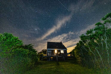 Das Haus ist nachts unter dem Sternenhimmel beleuchtet. - CAVF86761