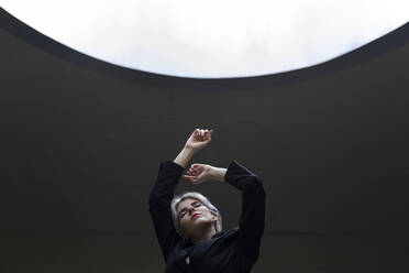 Stylish female professional wearing elegant suit standing against illuminated light in office - TCEF00835