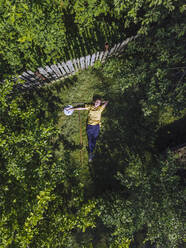 Aerial view of mid adult woman resting on grassy land in yard - KNTF04748