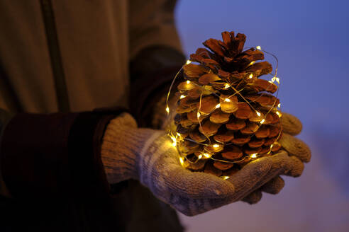 Illuminated pine cone held by teenage girl during Christmas - LBF03129