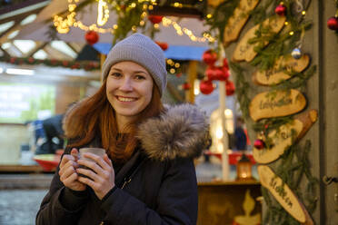 Glückliche Frau mit Kaffeetasse auf dem Weihnachtsmarkt - LBF03131