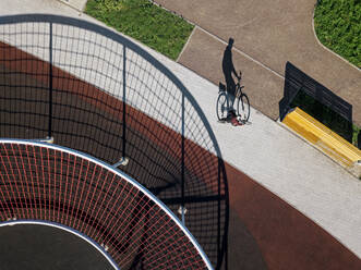 Man cycling on path in sports field, aerial view - KNTF04784