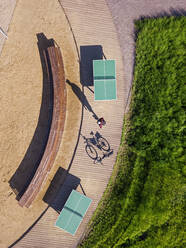 Russia, Tikhvin, Man with bicycle on boardwalk with table tennis tables, aerial view - KNTF04789