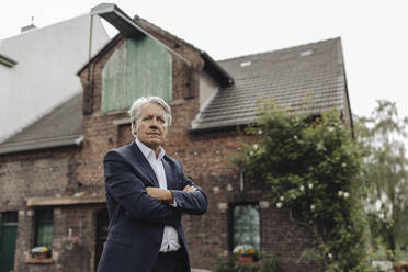 Portrait of a senior businessman in front of a farmhouse - GUSF04016