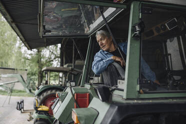 Älterer Mann fährt Traktor auf einem Bauernhof - GUSF04020