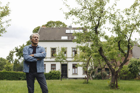 Älterer Mann steht in einem ländlichen Garten, lizenzfreies Stockfoto