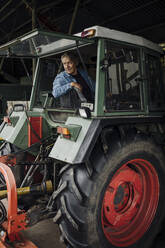 Älterer Mann fährt Traktor auf einem Bauernhof - GUSF04114