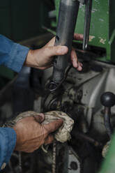 Close-up of man cleaning tractor - GUSF04130