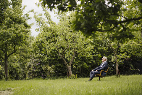 Senior businessman sitting on a chair in a rural garden stock photo