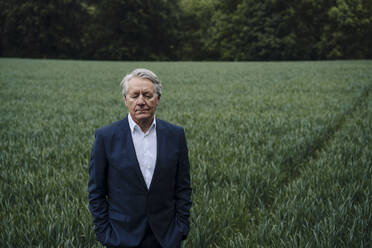 Portrait of a senior businessman with closed eyes on a field in the countryside - GUSF04159