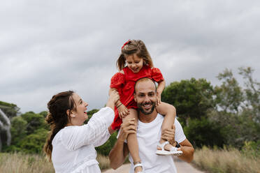 Cheerful family enjoying at countryside against cloudy sky - EGAF00358