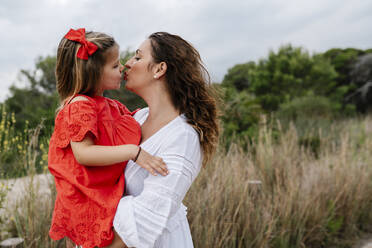 Affectionate mother and daughter kissing at countryside - EGAF00363