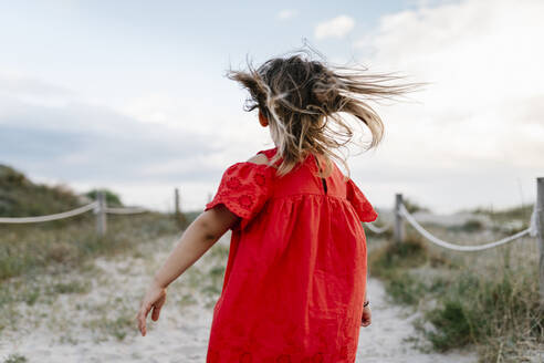 Verspieltes Mädchen spaziert am Strand gegen bewölkten Himmel - EGAF00379