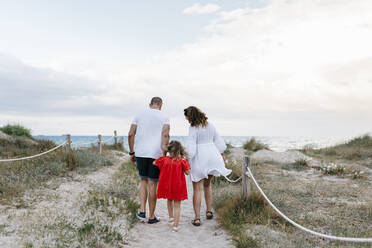 Family walking on trail at beach against cloudy sky - EGAF00380