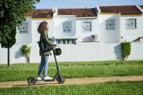 Junge Frau fährt in der Stadt mit einem Elektroroller - KIJF03149