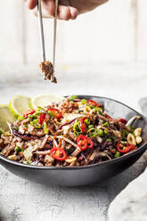 Fried rice noodles with vegetables, Pad Thai style with boys hand holding chopsticks - SBDF04279