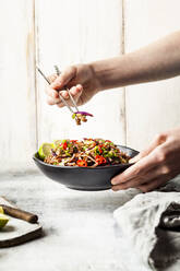 Fried rice noodles with vegetables, Pad Thai style with boys hand holding chopsticks - SBDF04280