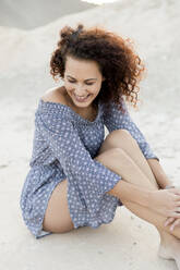 Glückliche junge Frau auf Sand sitzend auf dem Lande - LVVF00170