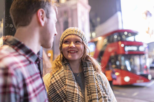 Junges Paar im Gespräch am Piccadilly Circus mit Doppeldeckerbus im Hintergrund - WPEF03125