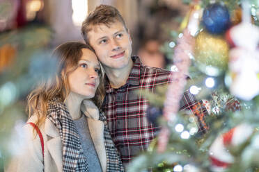 Loving young couple looking at Christmas tree and lights in city - WPEF03145