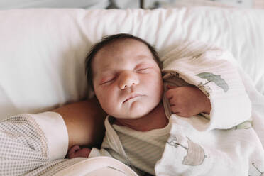 Nahaufnahme eines neugeborenen Mädchens, das auf dem Arm der Mutter im Krankenhaus schläft - GEMF03907