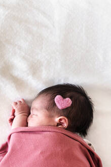 Neugeborenes Baby-Mädchen mit Herzform auf dem Kopf schlafend über Bett im Krankenhaus - GEMF03910