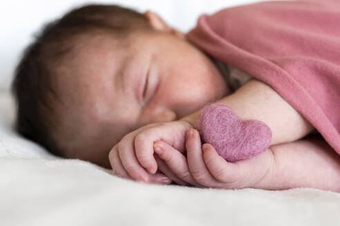 Nahaufnahme eines neugeborenen Mädchens mit Herzform, das auf einem Bett im Krankenhaus schläft - GEMF03911