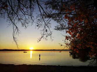 Silhouette eines im See stehenden Mannes bei Sonnenuntergang - ECPF00975