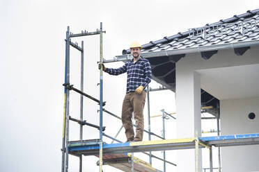 Bauarbeiter auf einem Gerüst bei klarem Himmel auf einer Baustelle - MJFKF00394