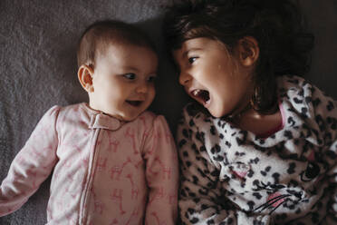 Girl screaming while looking at cute baby sister on bed - GEMF03918
