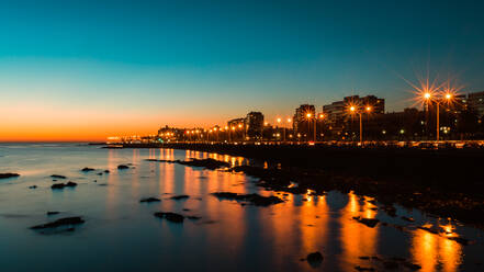 Beleuchtete Stadt am Meer gegen den Himmel bei Sonnenuntergang - EYF09375