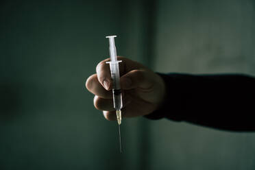 Cropped Hand Holding Syringe At Home - EYF09378