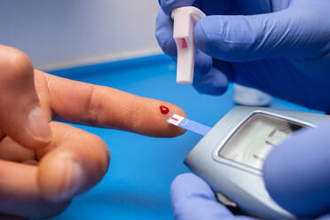 Cropped Hände des Arztes Doing Bluttest des Patienten - EYF09379