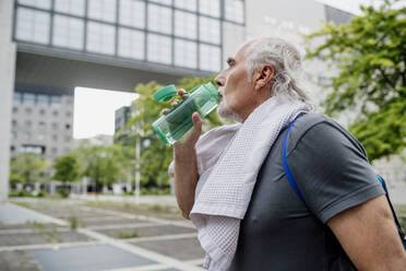 Nahaufnahme eines älteren Mannes, der Wasser trinkt, während er in der Stadt steht - MEUF01155
