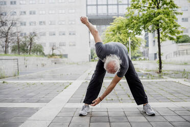 Älterer Mann, der auf dem Fußweg vor einem Gebäude in der Stadt trainiert - MEUF01162