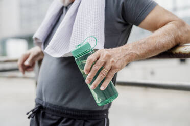 Nahaufnahme eines älteren Mannes, der eine Wasserflasche hält, während er in der Stadt steht - MEUF01174