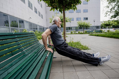 Älterer Mann balanciert beim Sport in der Stadt auf einer Bank - MEUF01180