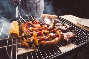 Mittelteil eines Mannes bei der Zubereitung von Speisen auf einem Barbecue-Grill - EYF09391